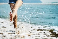 photo de jambes de femme donnant un coup de pieds dans l'eau sur la plage